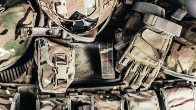 Capacete camuflado e luvas sobre equipamento militar, representando preparação tática.