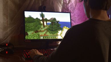 Jogador concentrado diante de um computador enquanto joga videogame em ambiente interno.