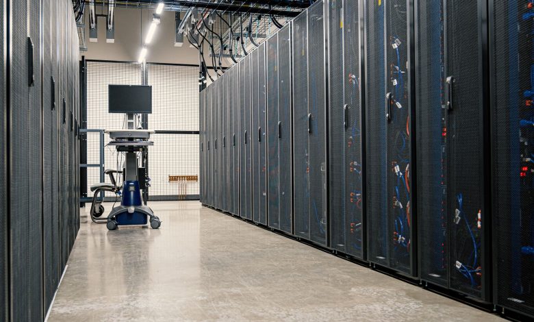 Racks metálicos com servidores, equipamentos de rede e cabos em um data center moderno.